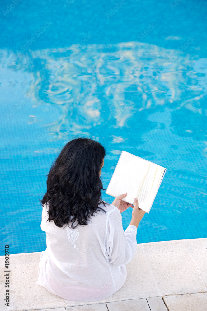 在游泳池读书的迷人女士