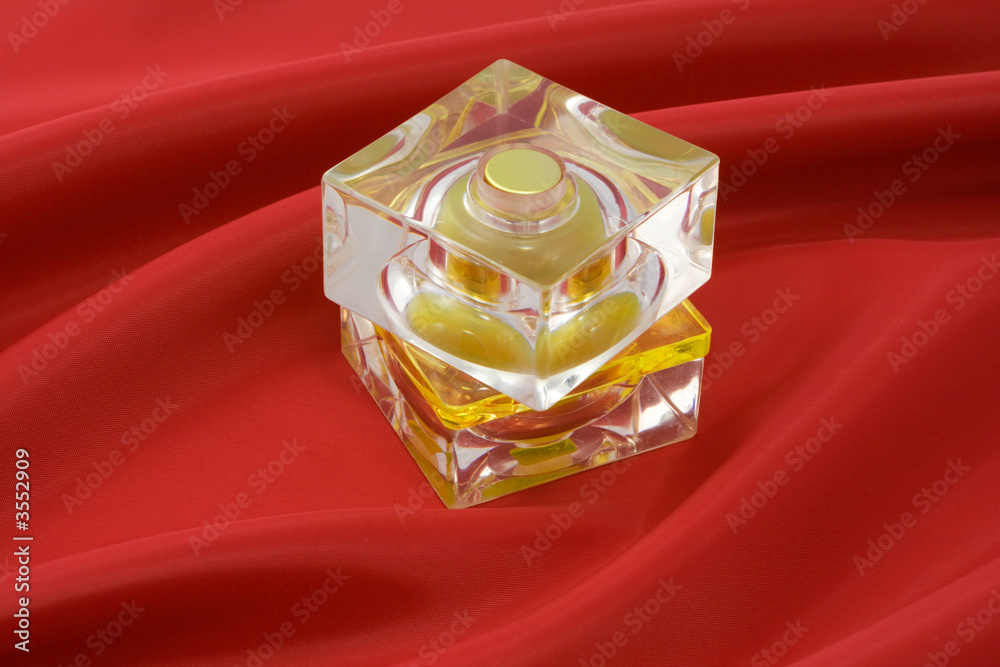 红色丝绸布上的黄色香水瓶。