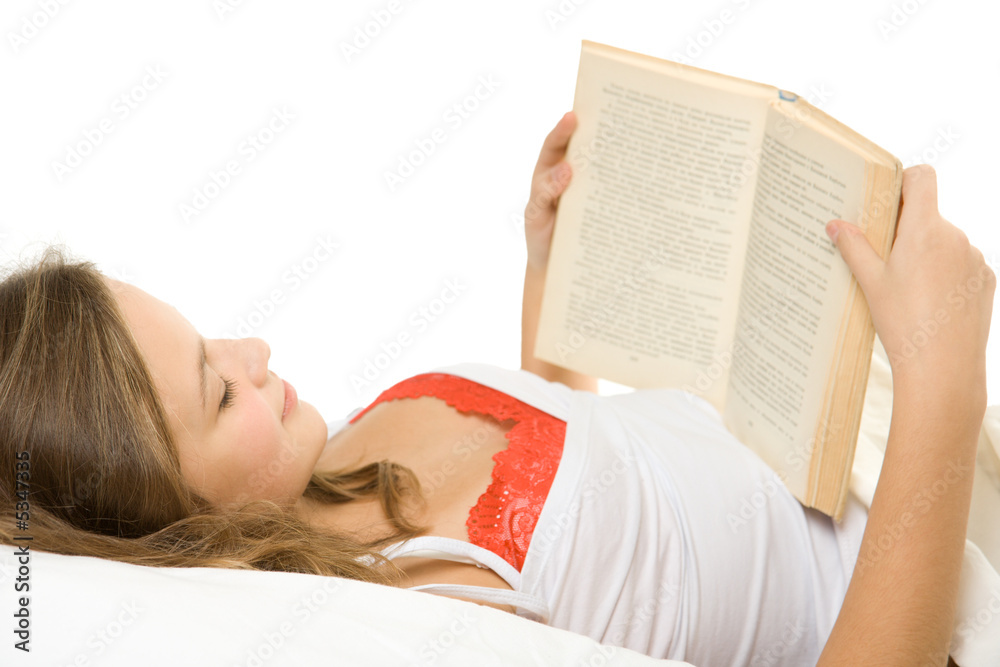 年轻女孩在床上看书。
