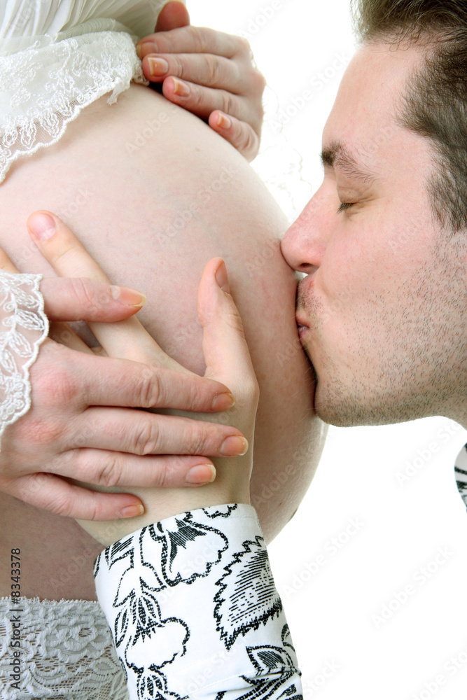 Husband kiss his pregnant wife belly. Isolated on white.