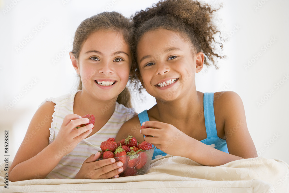 两个年轻女孩在客厅里吃草莓，面带微笑
