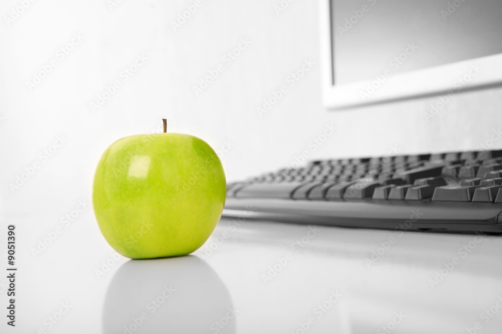 绿色苹果在电脑背景上的桌子上