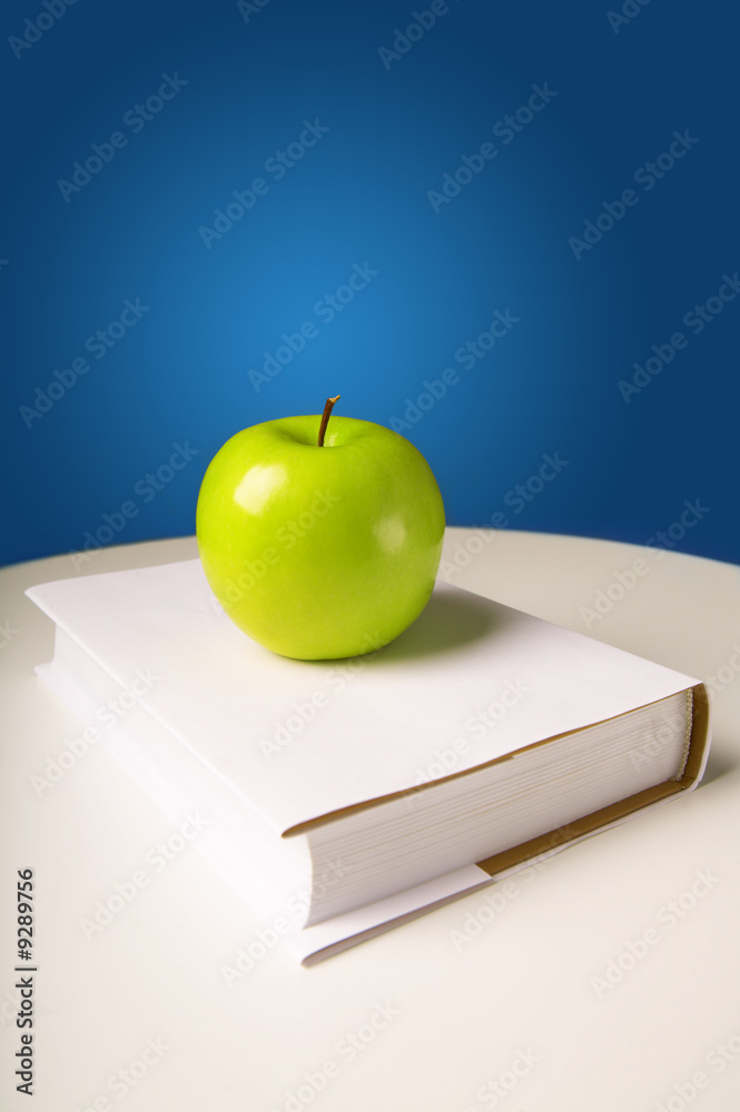The green shining apple lays on the book