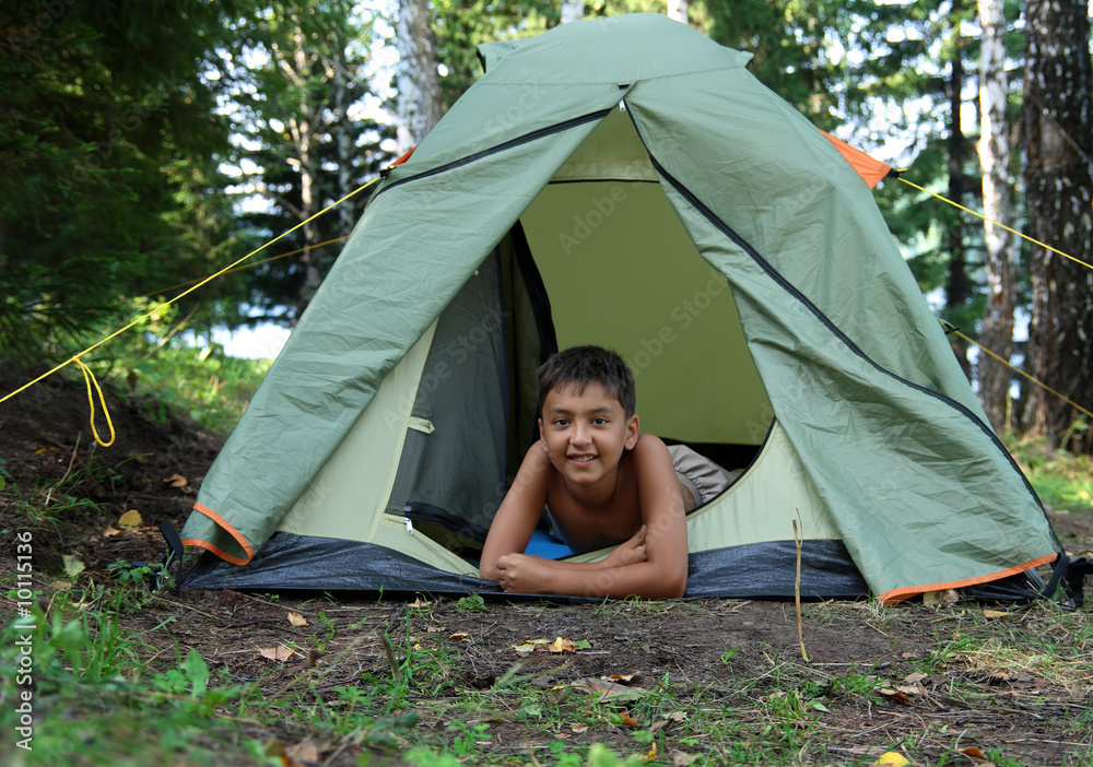 森林露营帐篷里的微笑男孩