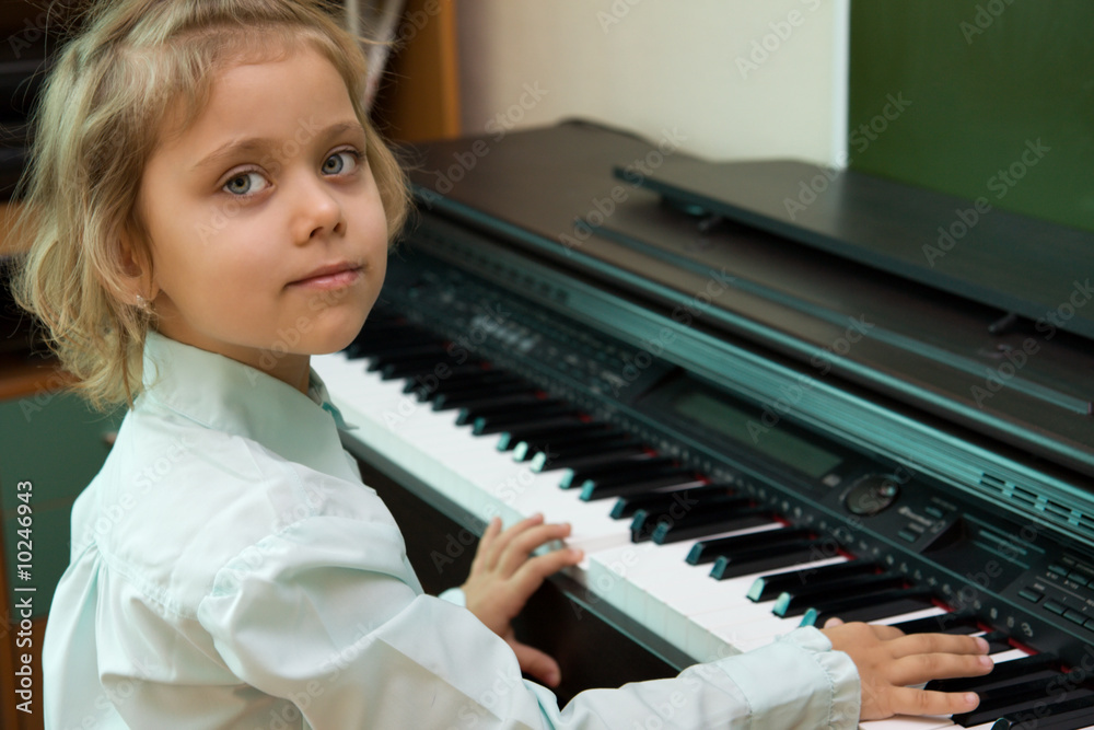 小高加索女孩在电动钢琴上演奏