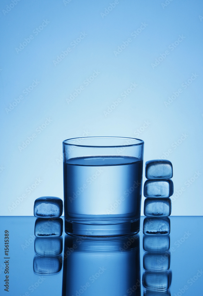 蓝色背景的一杯水和冰块