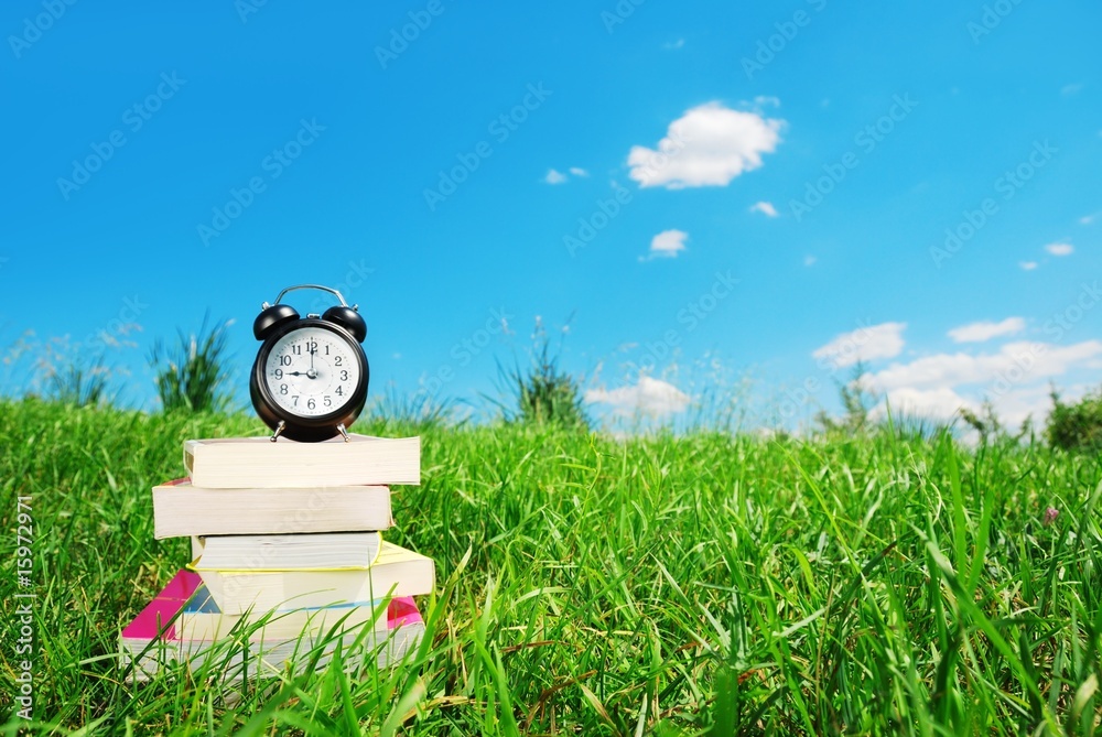 草地上一摞带闹钟的书