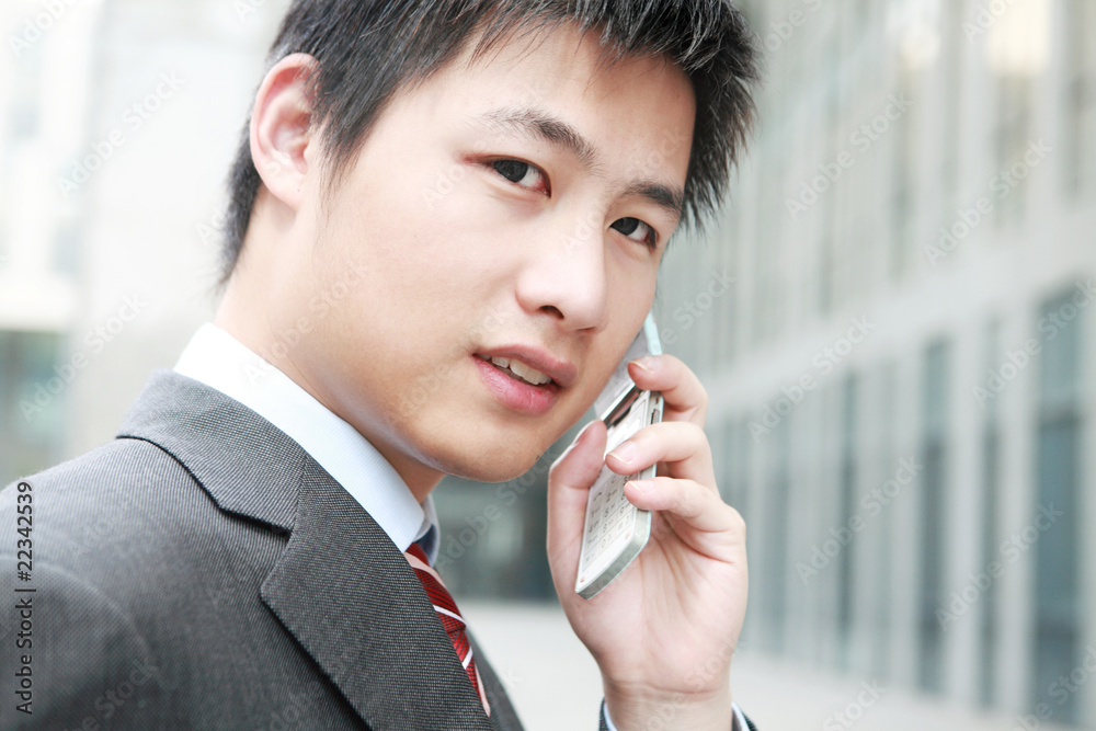 一个年轻的亚洲商人在户外接电话
