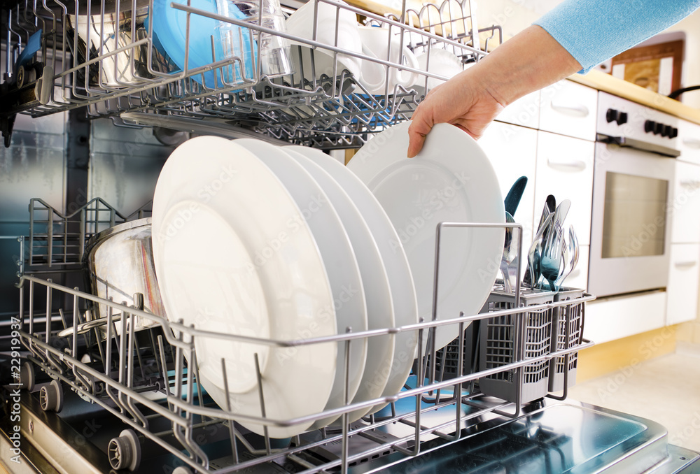 女性双手将碗碟放入洗碗机
