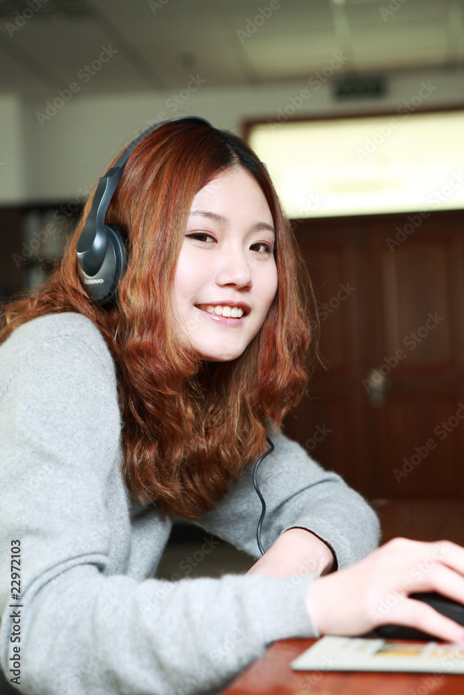 亚洲女孩坐在电脑前听音乐