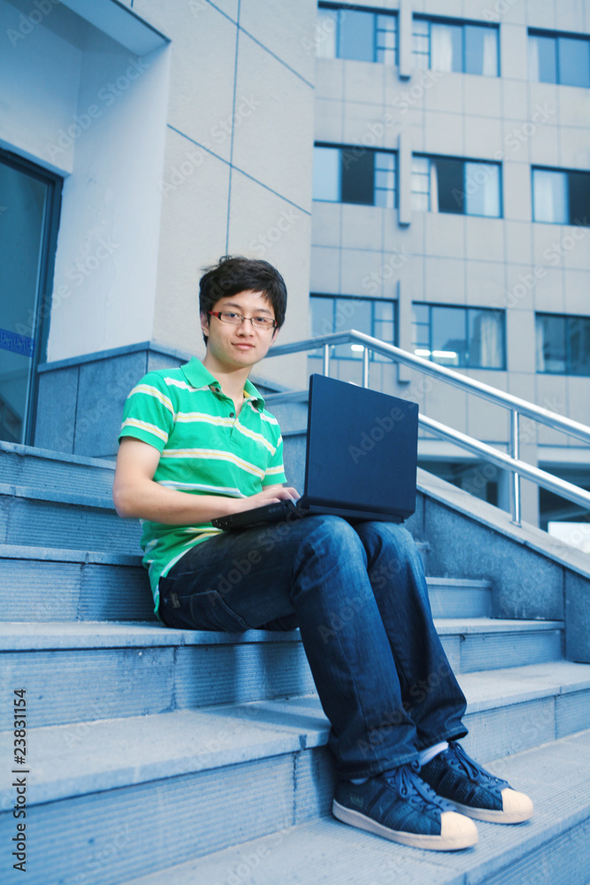 带笔记本电脑的亚洲男学生