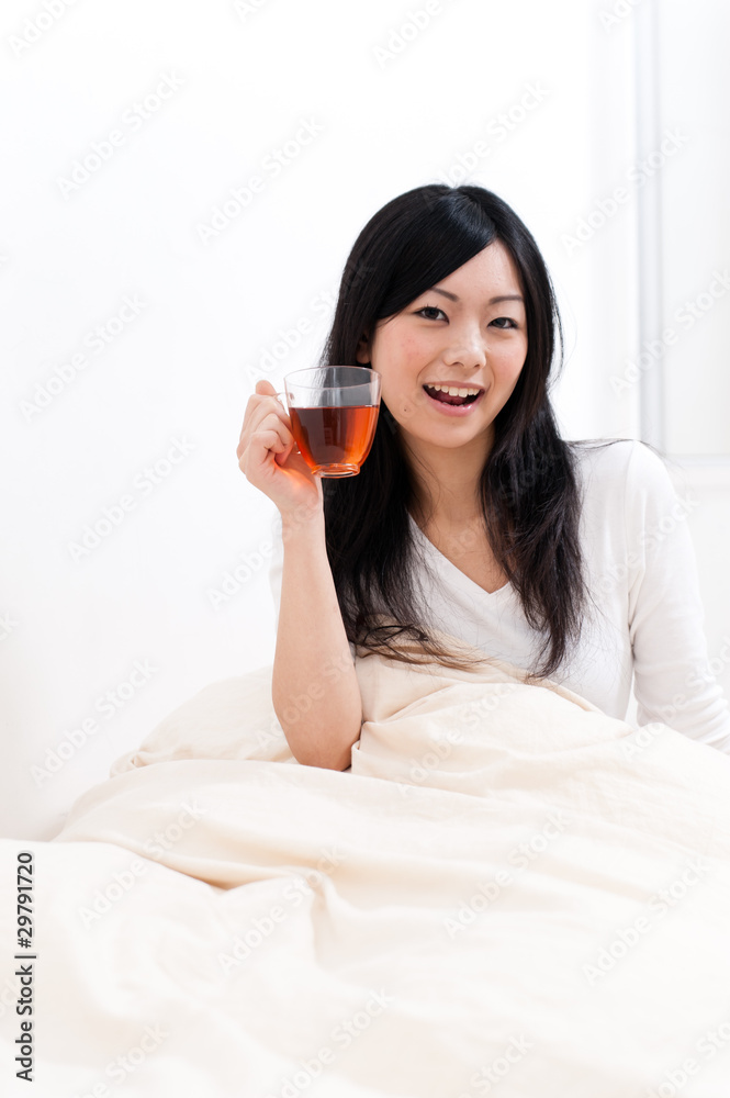 beautiful asian woman drinking tea on the bed