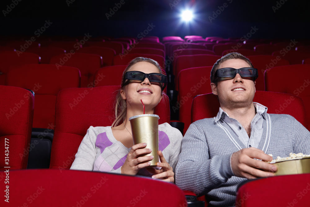 戴着3D眼镜在电影院看电影的迷人情侣