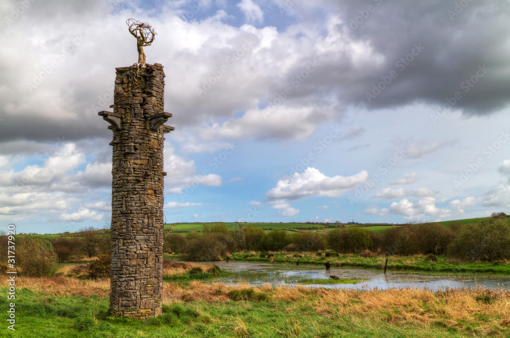 爱尔兰景观上方带有金属树符号的石塔