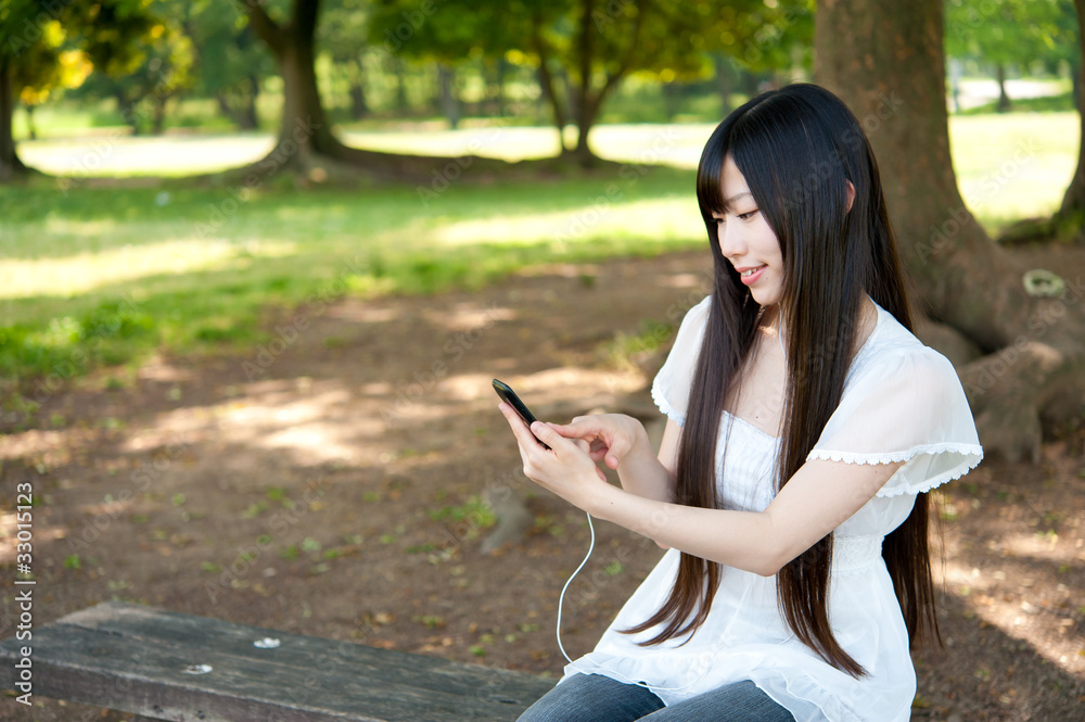在公园里使用智能手机的亚洲美女