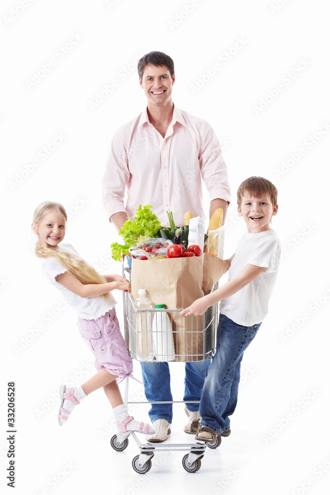 一名男子和两名儿童带着一辆装有食物的手推车