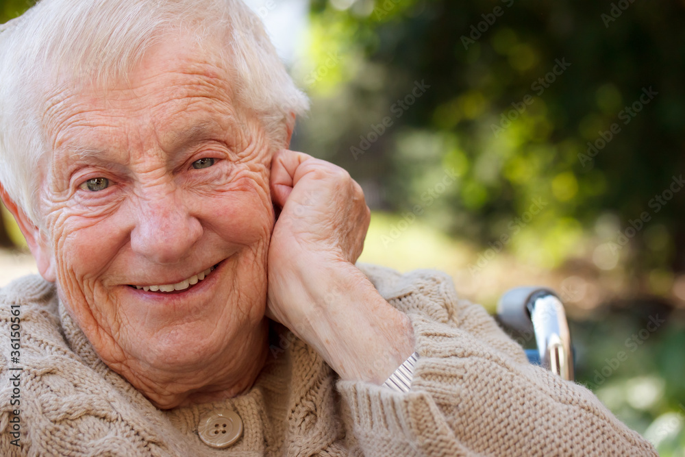 快乐的坐在轮椅上的老太太在外面微笑