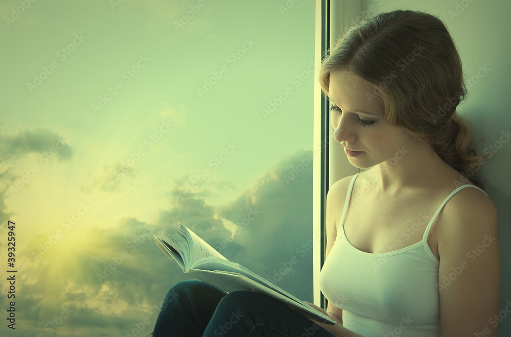 美丽的年轻女子坐在窗户边看书i