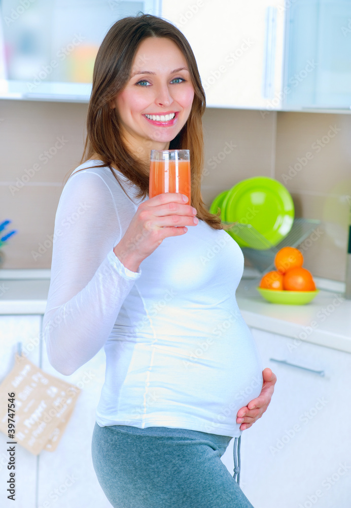 怀孕的年轻女子在家厨房喝新鲜果汁