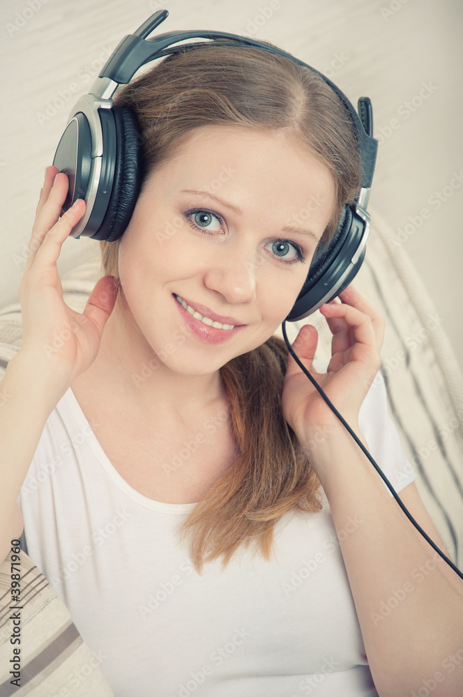 美丽的年轻女子喜欢戴着耳机听音乐