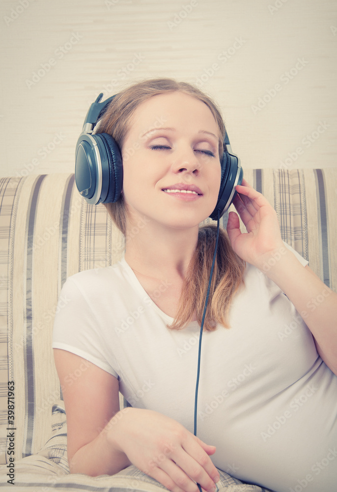 美丽的年轻女子一边用耳机听音乐，一边唱歌