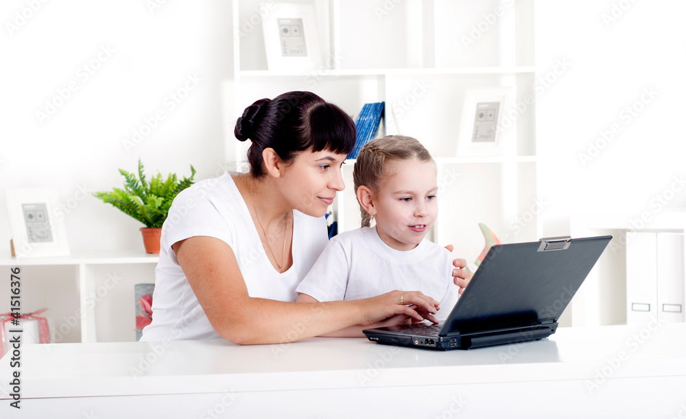 妈妈和女儿正在一起为一台笔记本电脑工作