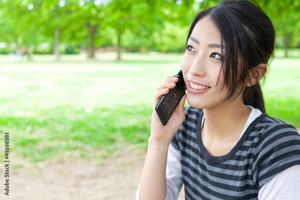 魅力四射的亚洲女人在公园里用手机聊天