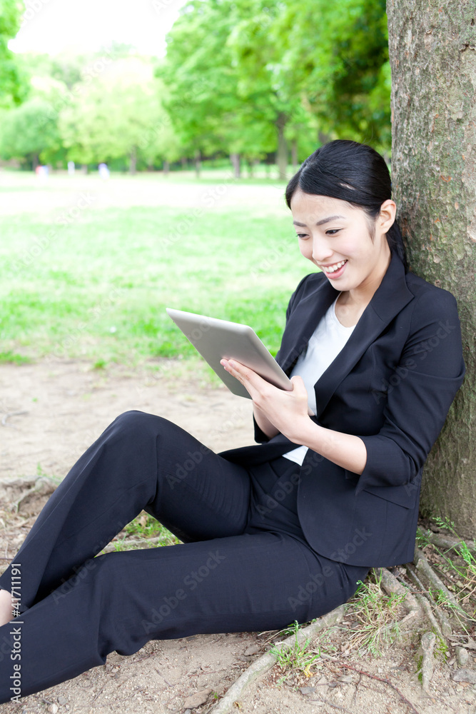 asian businesswoman using tablet in the park