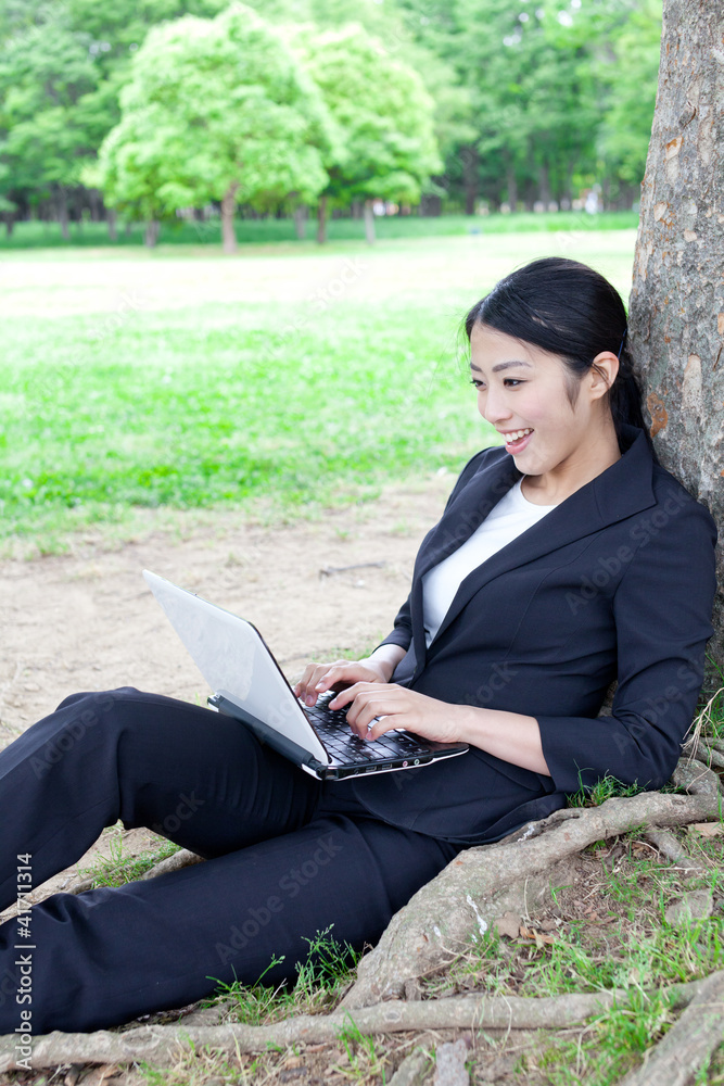 asian businesswoman using laptop in the park