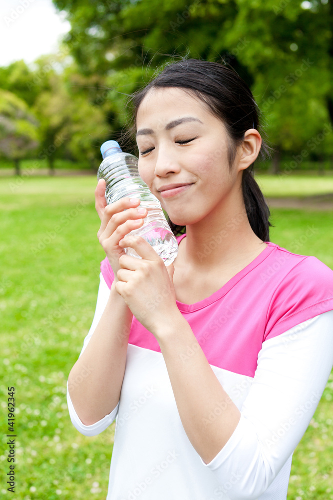 年轻的亚洲女人在公园里喝水