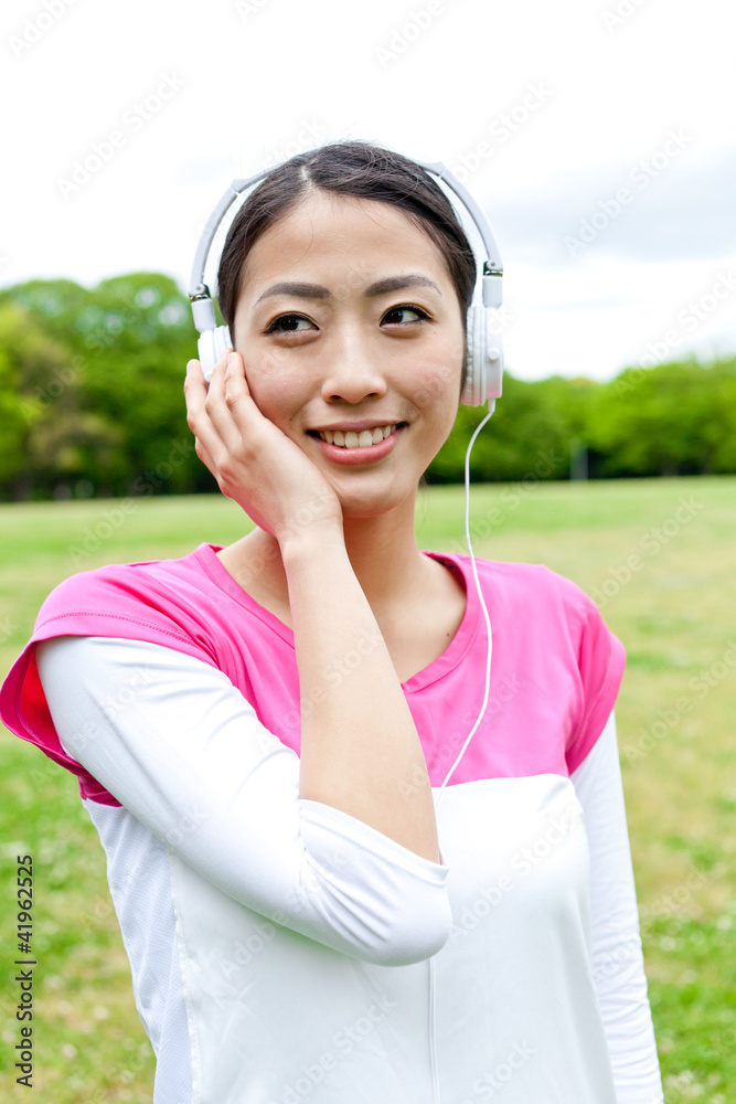 young asian woman listening music in the park