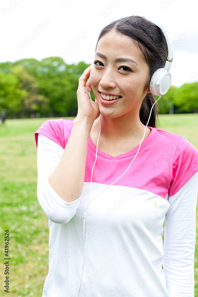 young asian woman listening music in the park