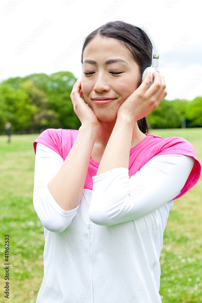 年轻的亚洲女人在公园里听音乐