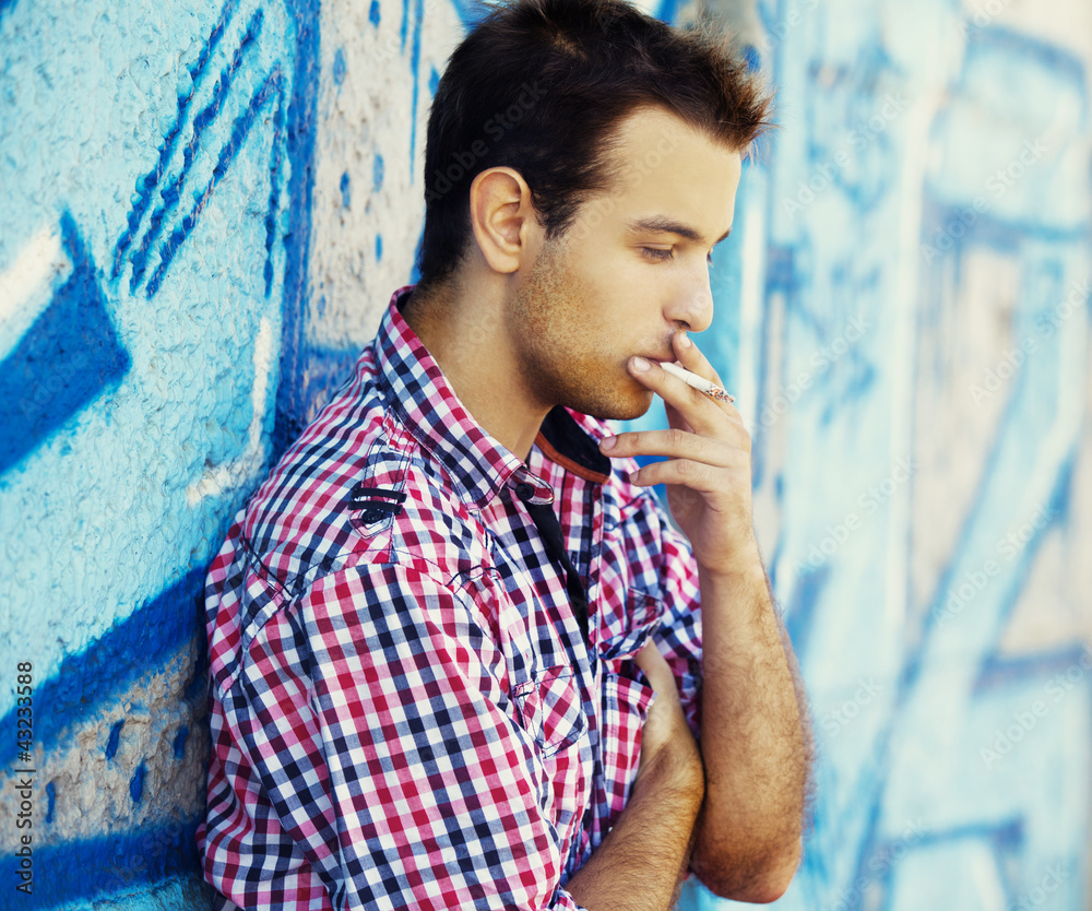 年轻的十几岁男孩在涂鸦墙附近吸烟。