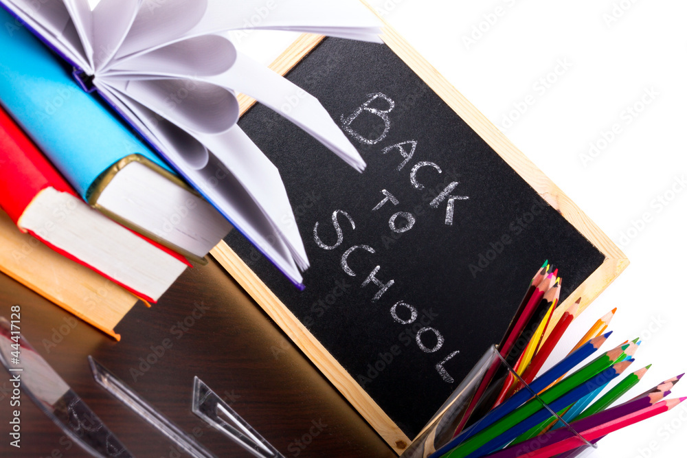 Back to school sign on a blackboard with books and pencils