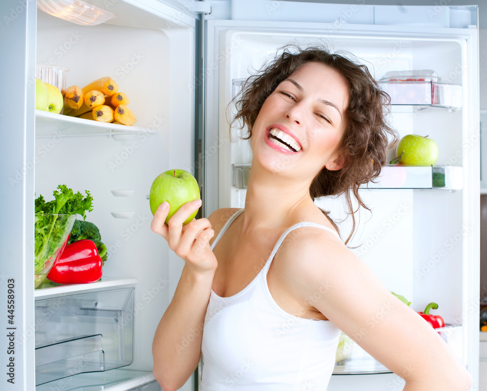 冰箱附近的年轻美女拿着新鲜苹果