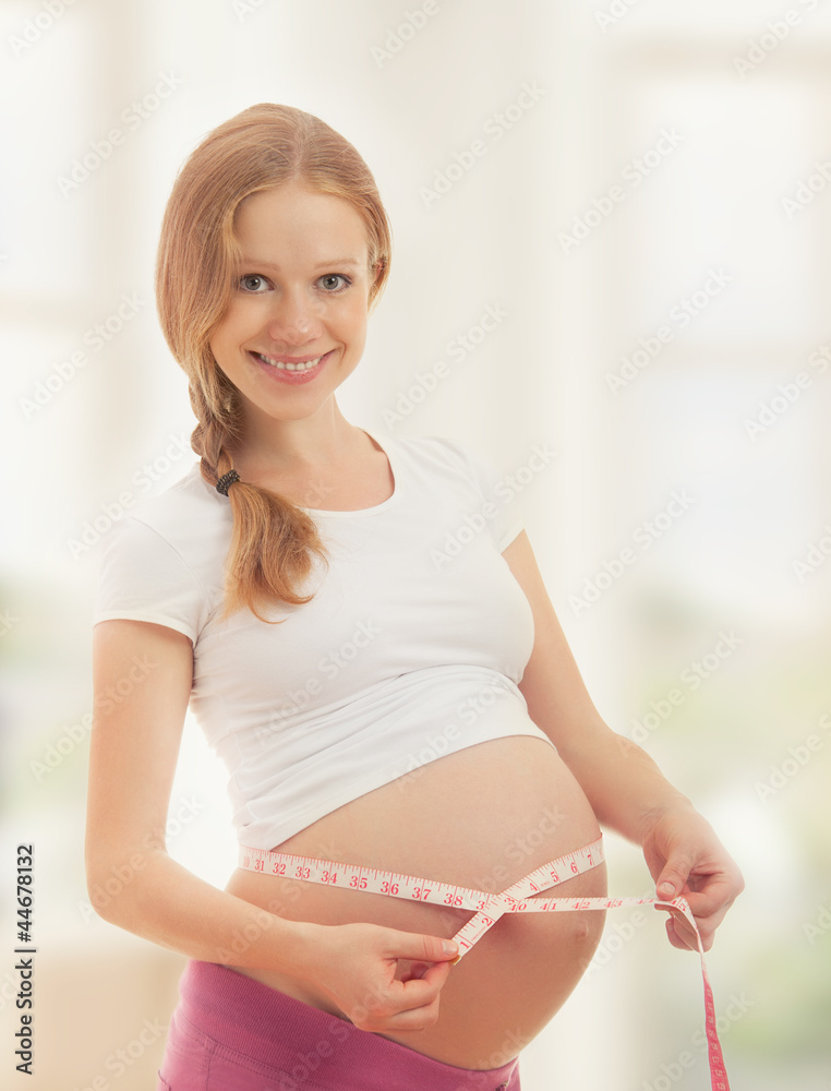 Pregnant woman with tape measuring her belly