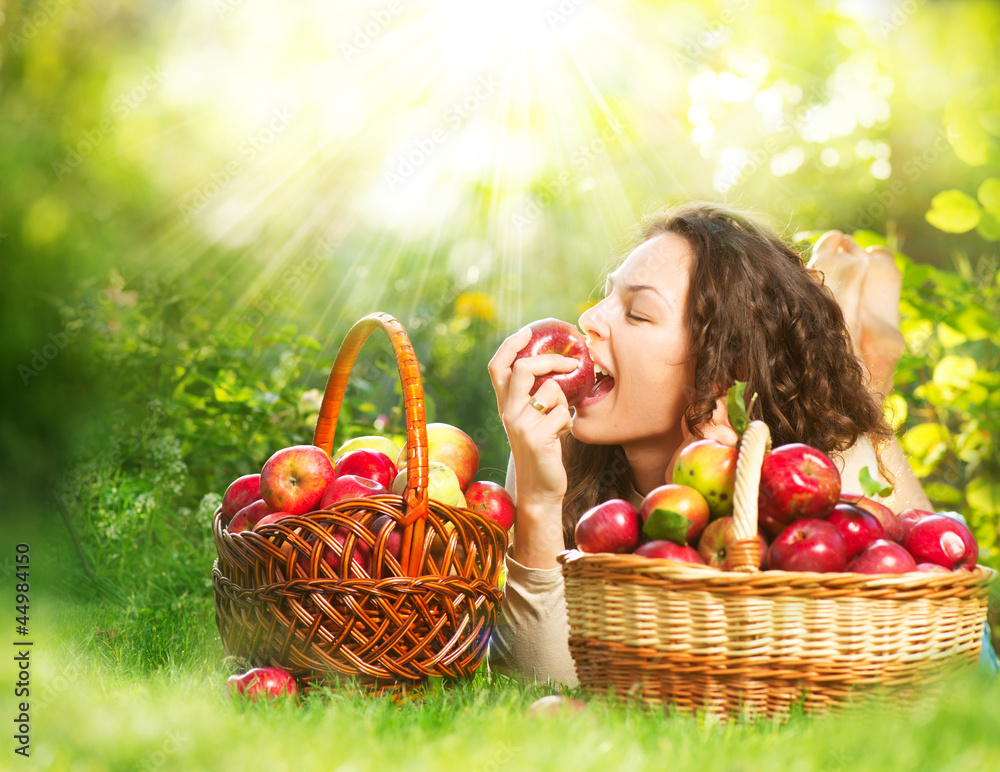 美丽女孩在果园吃有机苹果