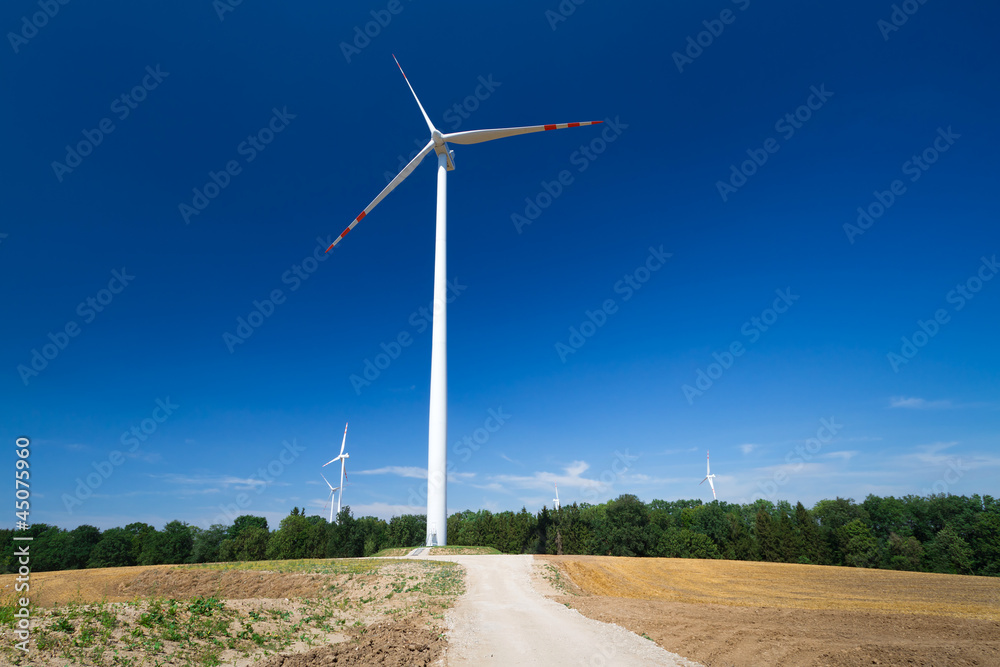 Wind turbine over blue sky on the summer field