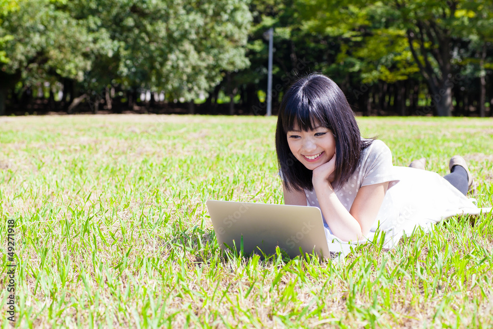 一个在公园里使用笔记本电脑的亚洲活跃女性