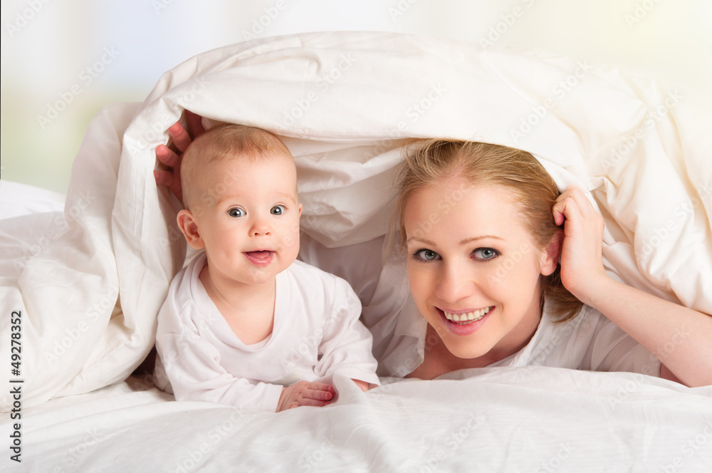 幸福的家庭。母亲和婴儿在毯子下玩耍