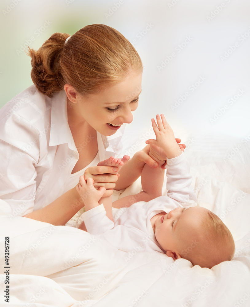 happy family. mother playing with her baby in bed