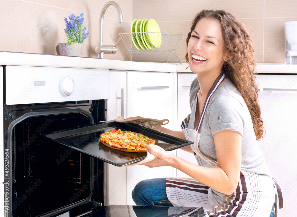 快乐的年轻女人在家做披萨