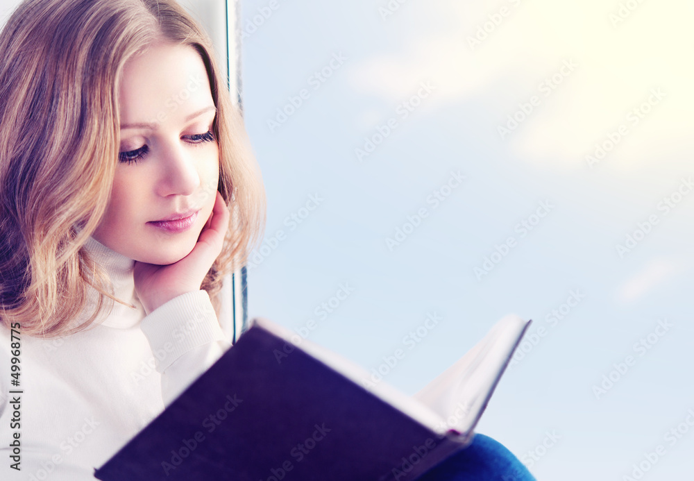 年轻漂亮的女人坐在窗户边看书