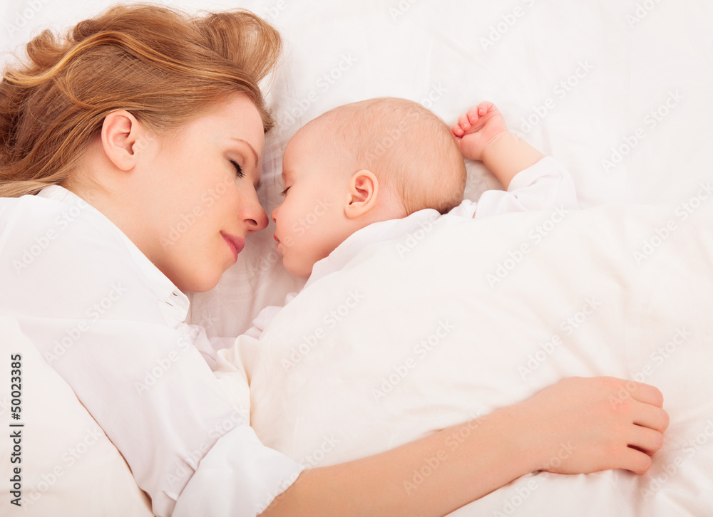 妈妈抱着一起睡在床上的新生儿