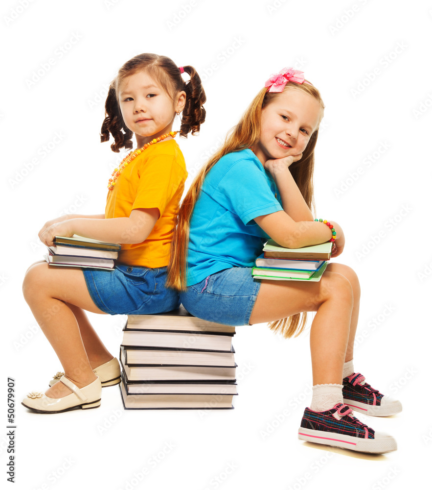 两个女孩坐在书上