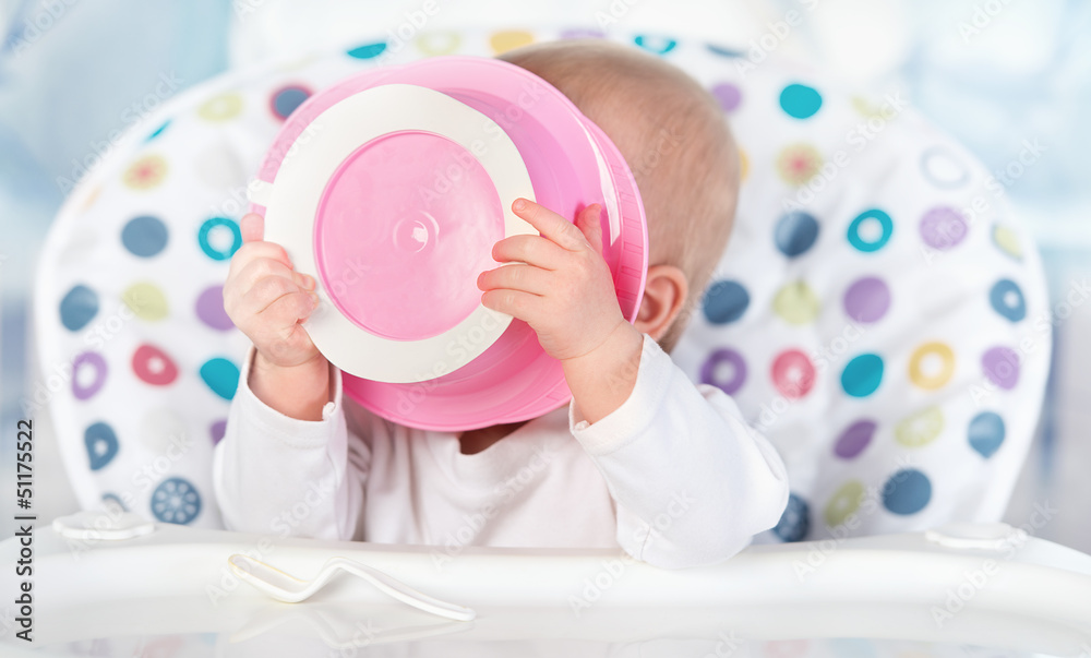 有趣的婴儿正在吃粉红色的盘子