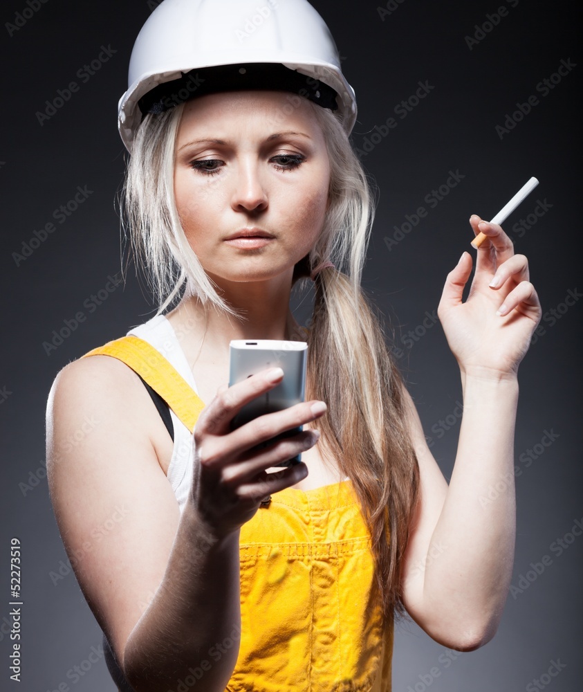 年轻的建筑师，女性建筑工人，香烟和电话