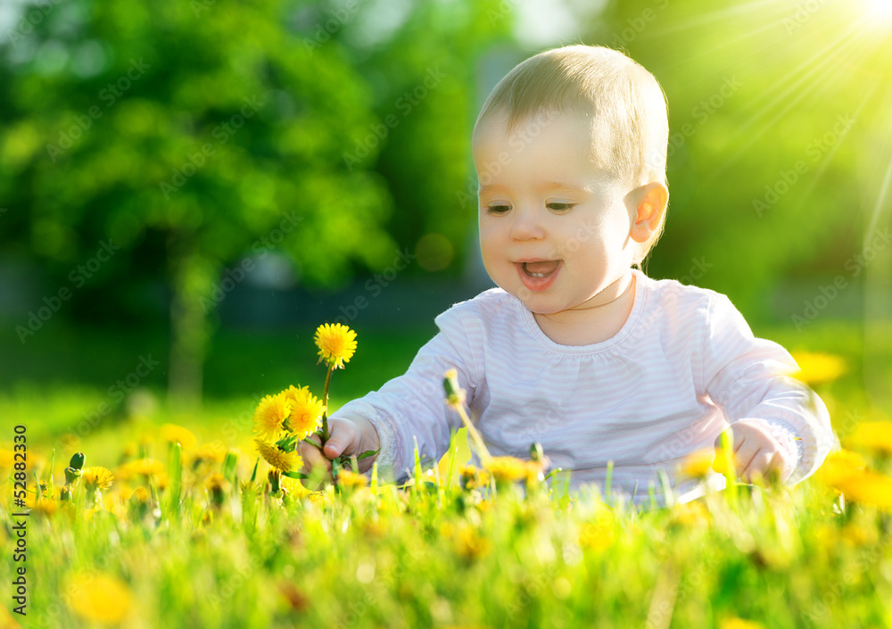 绿色草地上的女婴，草地上开着黄色的花朵蒲公英