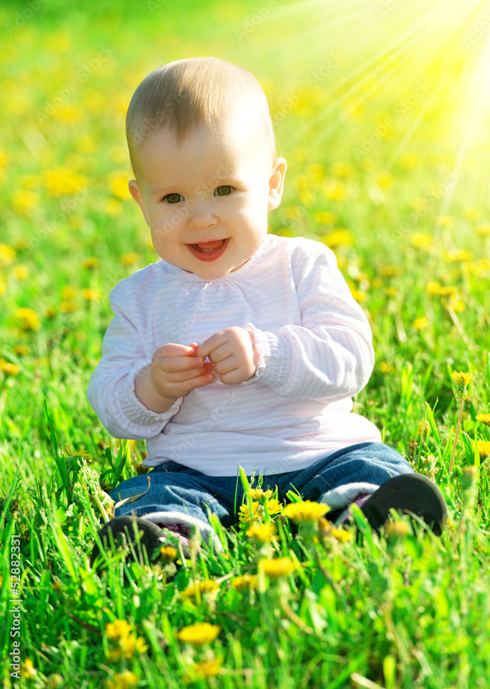绿色草地上的女婴，草地上开着黄色的花朵蒲公英